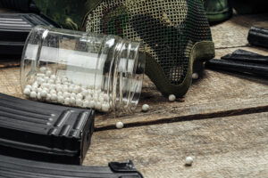 Close up photo of airsoft gun magazine and airsoft balls on wooden background